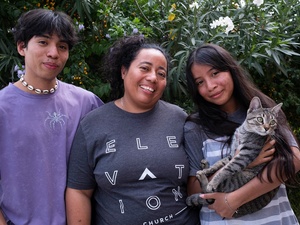 Al centro, una mujer con su hija y su hijo adolescentes. Su hija, quienestá a su lado izquierdo, sostiene entre sus brazos a un gato