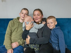 A mother and her three children sit on a couch