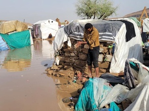 Flooding surrounds shelters and people's belongings at an IDP site.