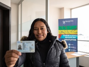 A woman holds up an ID card.