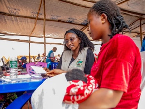 A woman siting in a UNHCR registration centre while holding her baby