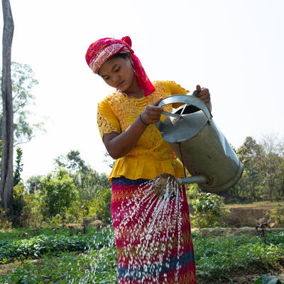 A young woman waters vegatables