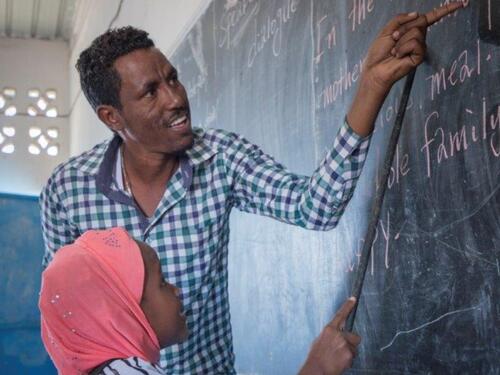 A teacher and his student in front of a black board.