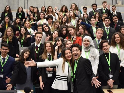 A group of young people in a conference room smile for the camera 