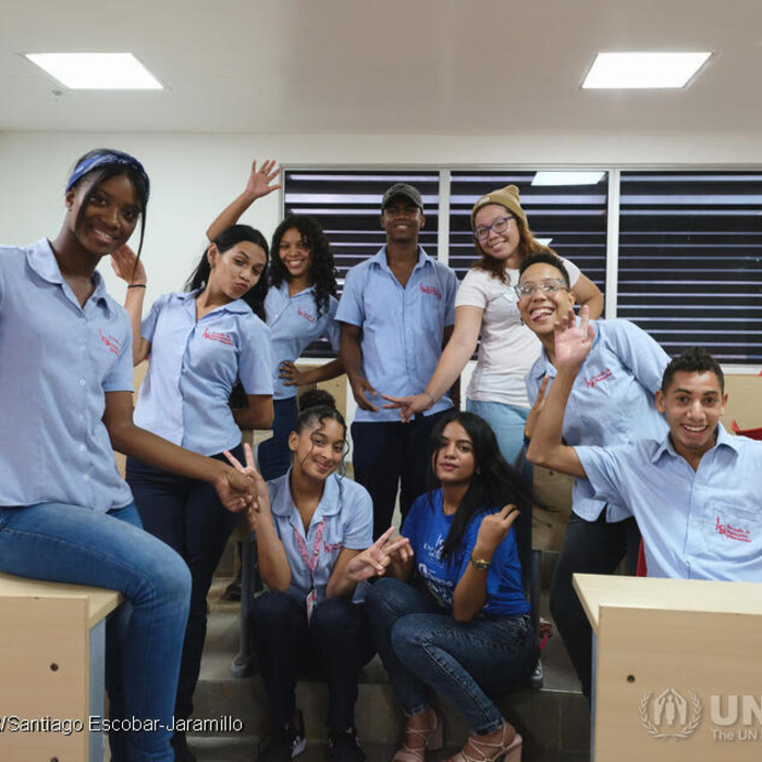 A group of students sit in a classroom posing for the camera.