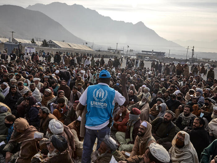 A UNHCR staff member assists displaced families waiting to receive winter cash assistance in Kabul.