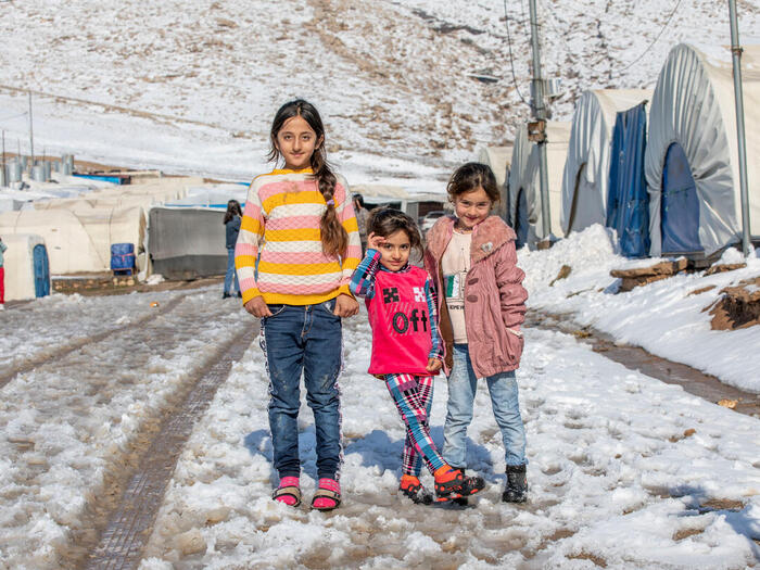 Young girls posing in front near their shelter after playing in the snow at Essian IDP camp near Duhok.