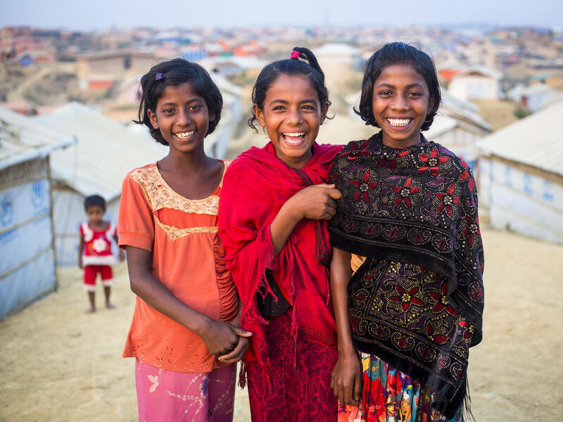 Three girls smile for the camera, in Kutupalong Refugee Camp.
