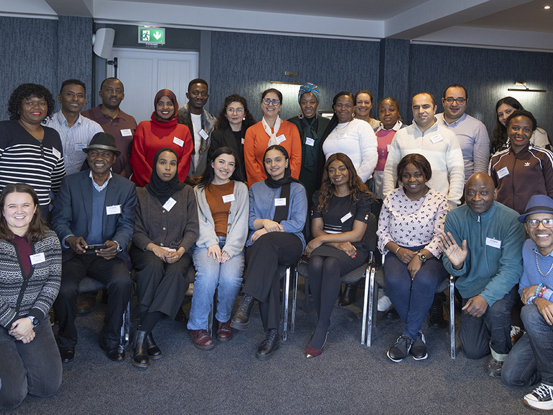 A large group of people in a conference room smile at the camera.