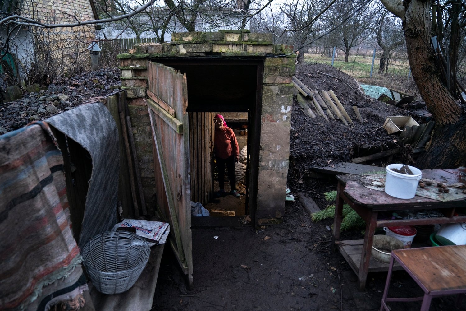 A woman stands in the doorway of an underground root cellar in her back yard.