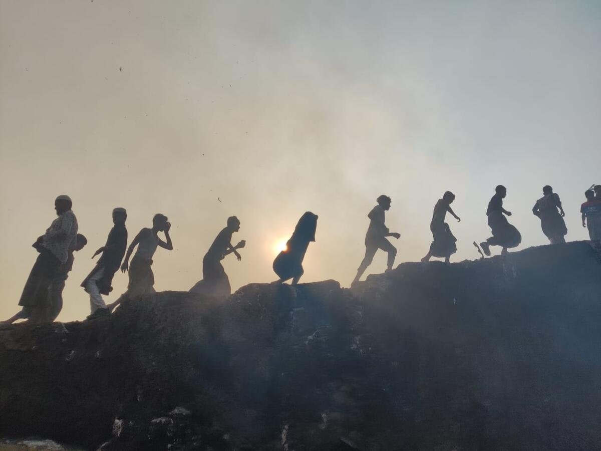 Refugees walk through smoke from a fire in Kutupalong’s Balukhali refugee camp