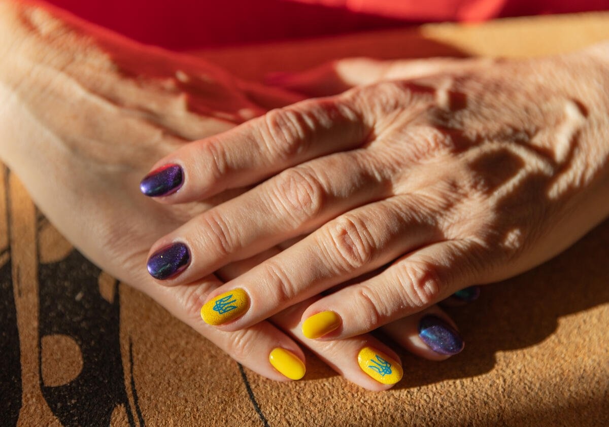 Two hands crossed over each other showing a manicure with Ukrainian symbols