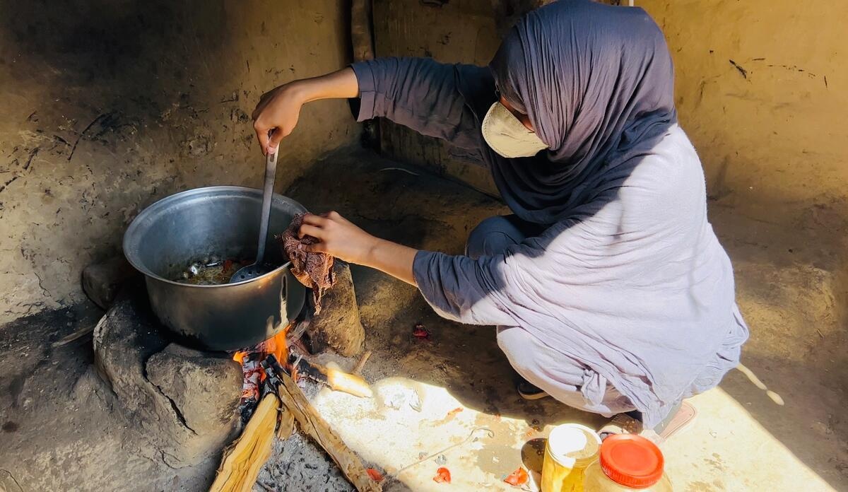 Amina prepares a meal sitting on the floor.
