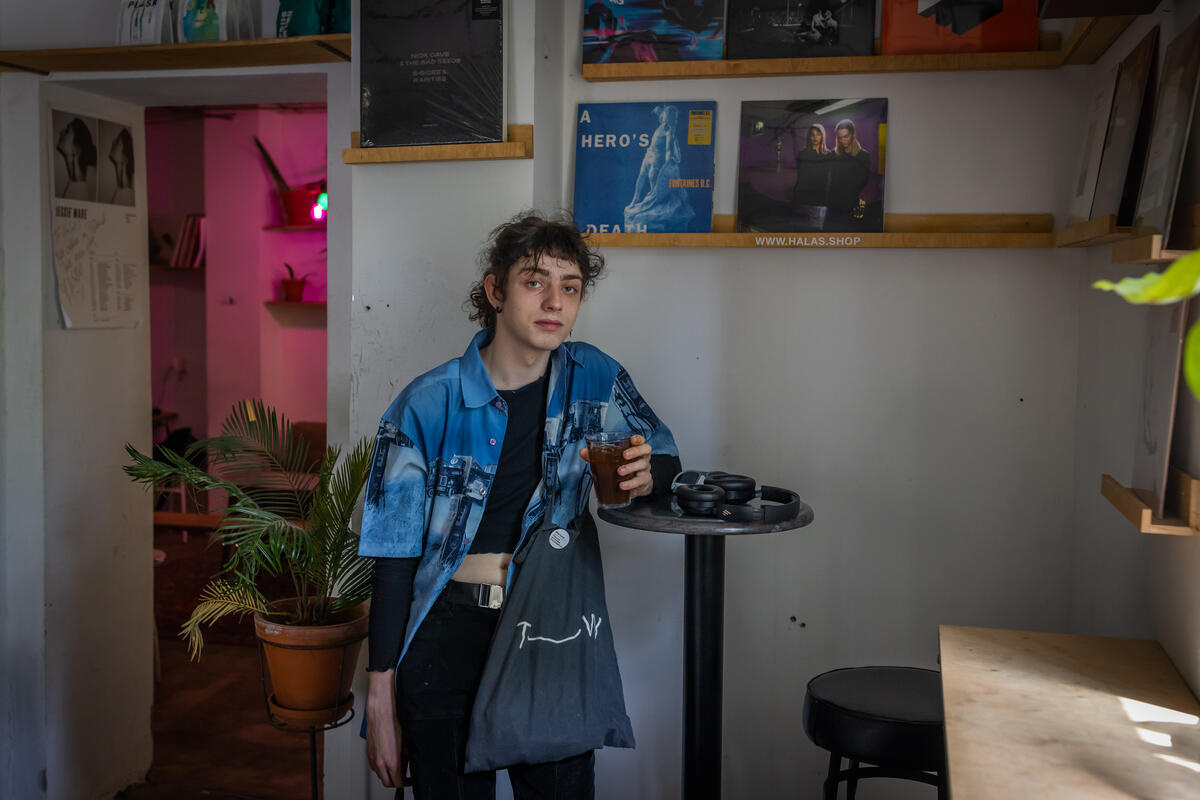 A woman pictured standing and leaning against a table in a café
