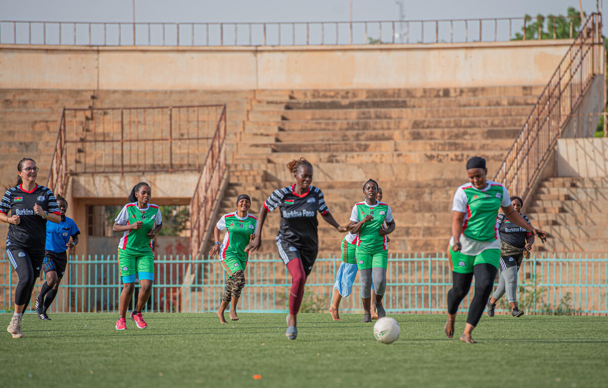 A group of people play football in an outdoor stadium