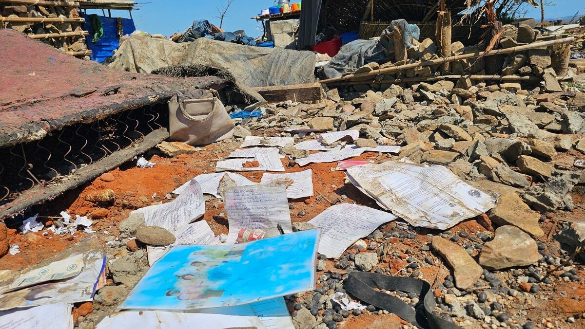 Rain-soaked school work scattered around the ruins of a house.