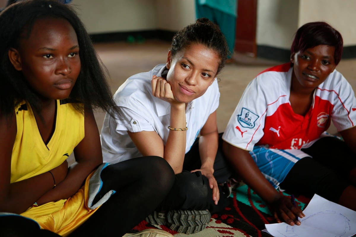 Gugu Mbatha-Raw sits on the ground with refugee women.