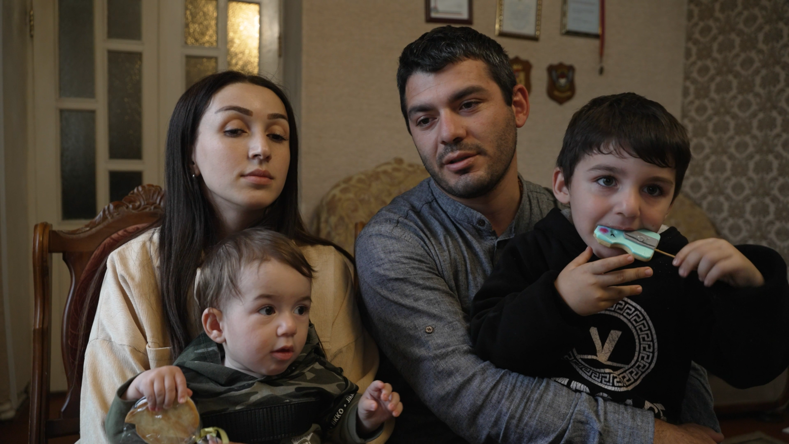 A couple sit with their two young children.
