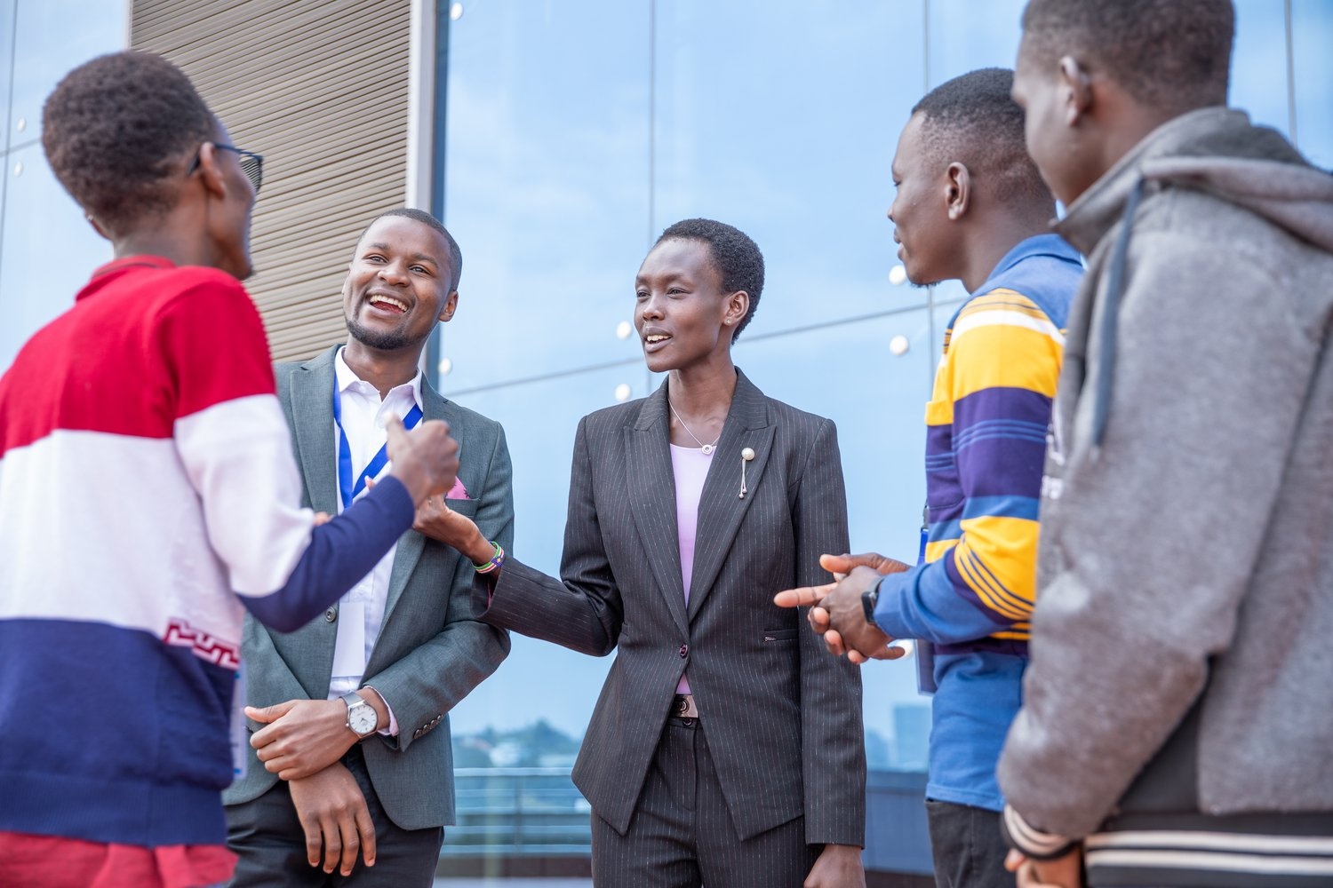A group of students talk outside a glass-fronted building.