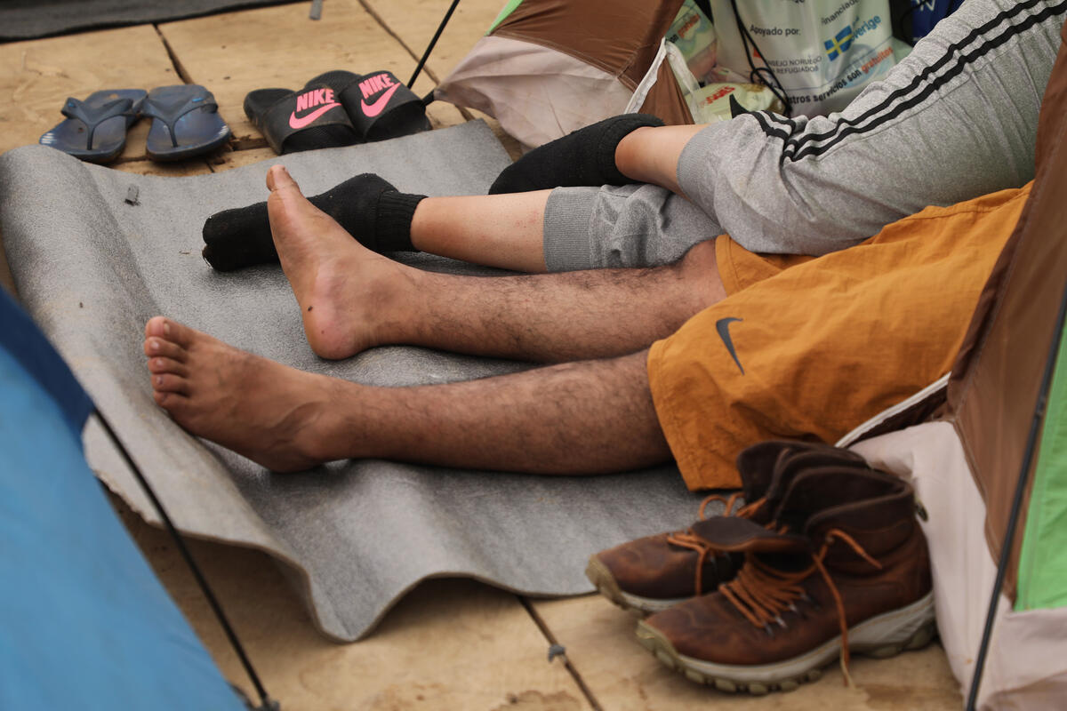 A man and a woman's legs poke out of a tent.