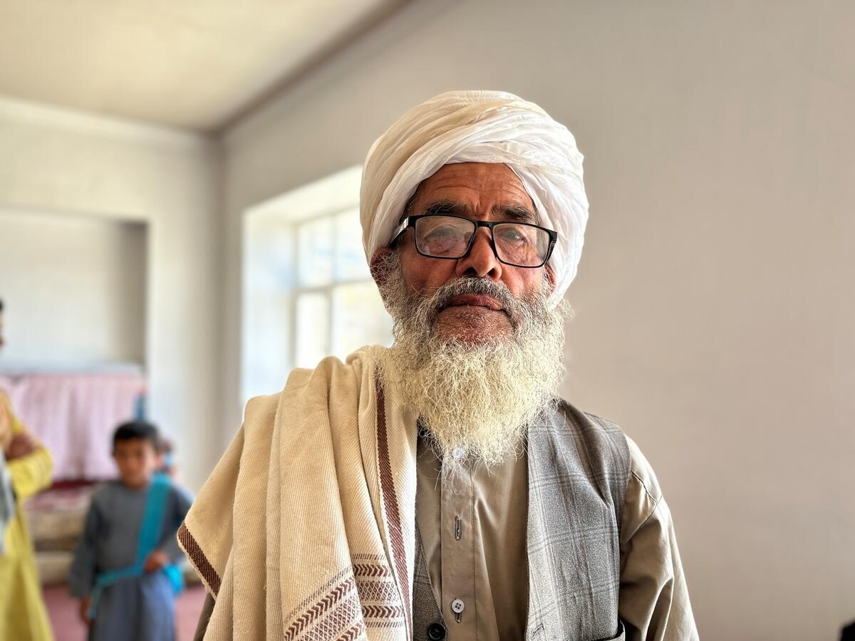 A man with a white beard wearing a headdress and glasses 