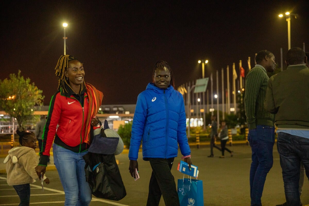 Two women walk towards an airport terminal.