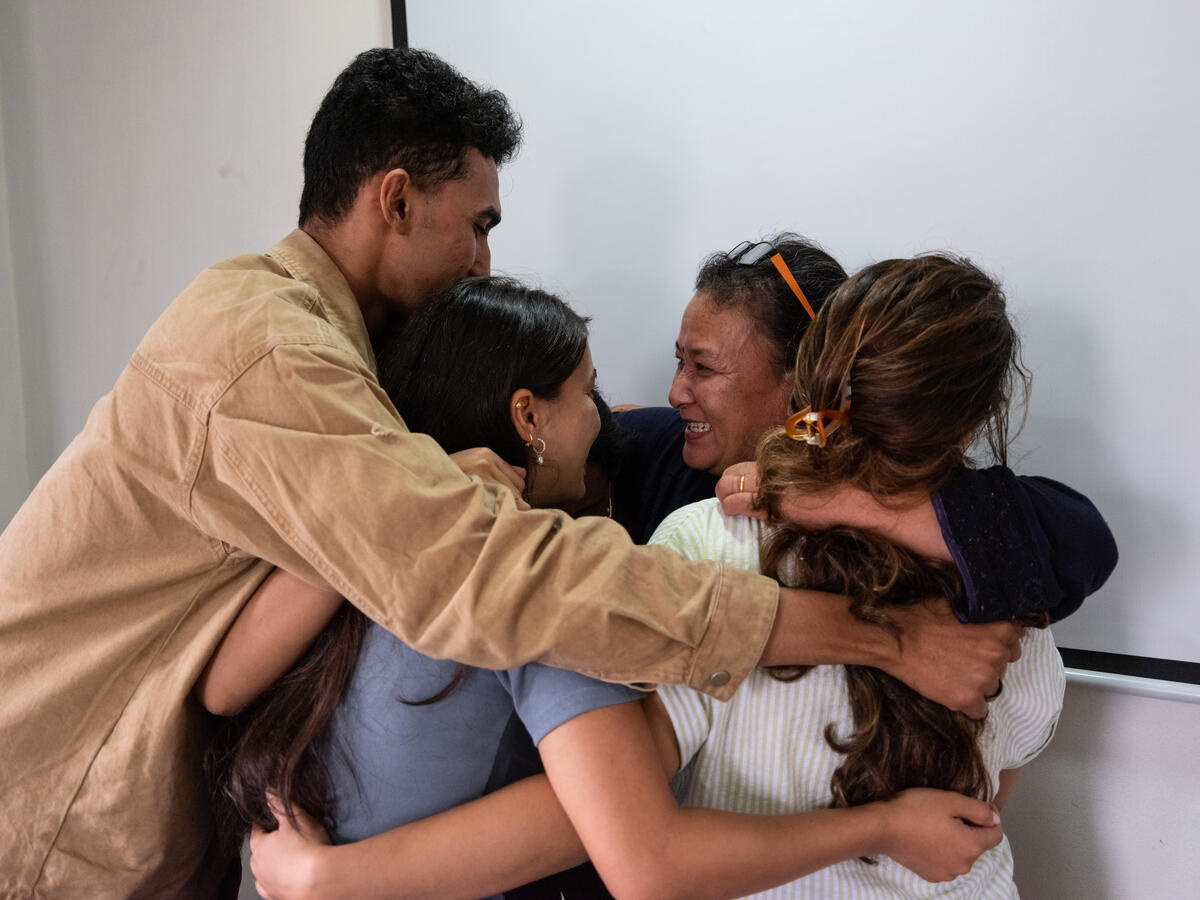 A man and three women embrace, smiling.