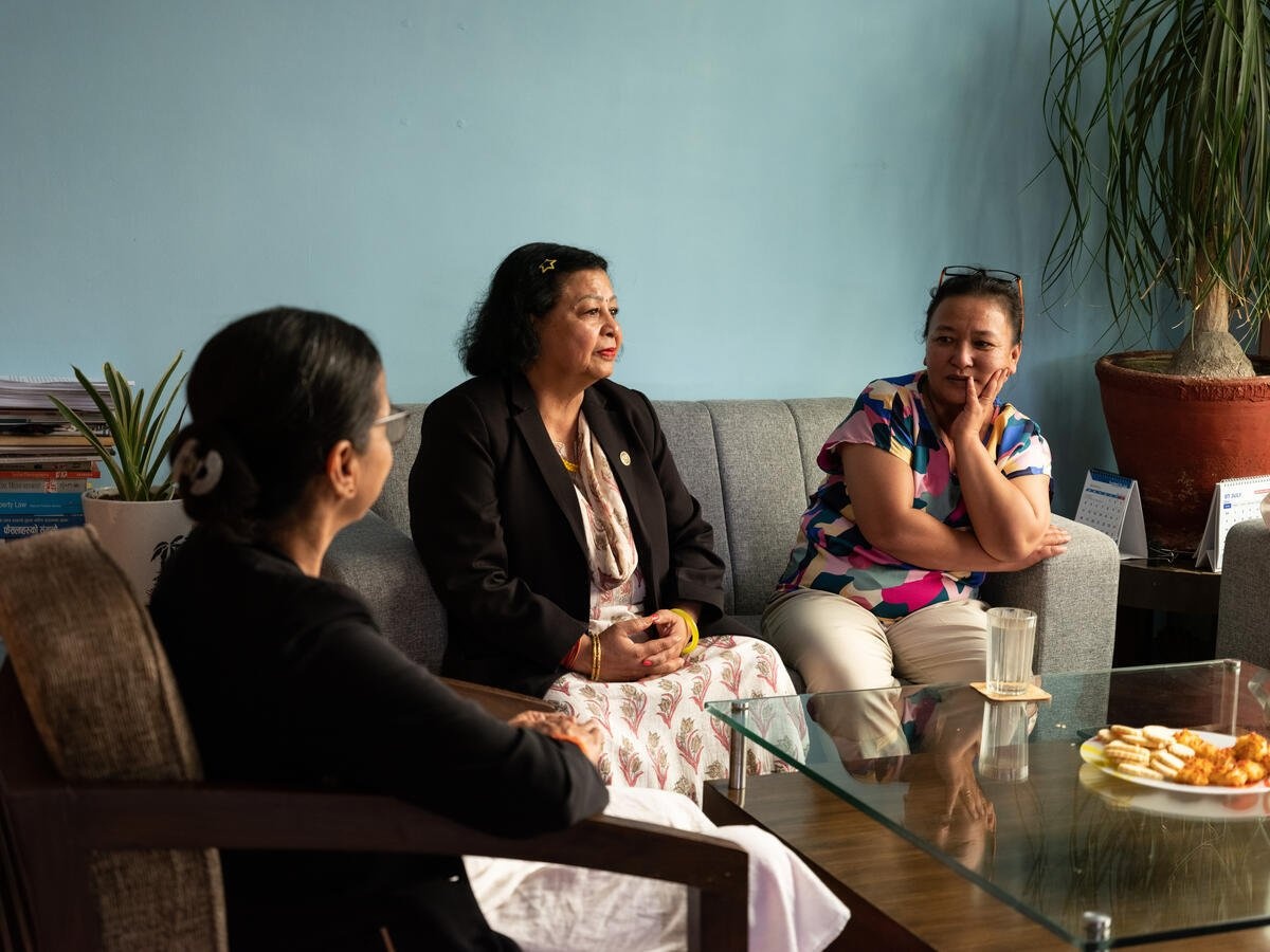 Three women sit on couches around a coffee table.