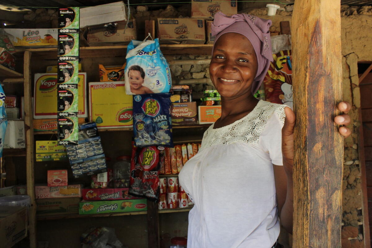 A young woman smiles from the doorway of a small shop.