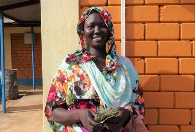 A smiling woman outside in front of a brick wall