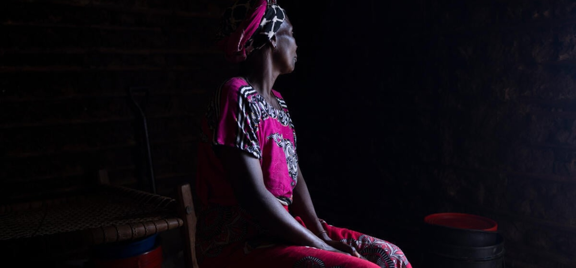 Portrait of a woman with her face turned away against a dark background.