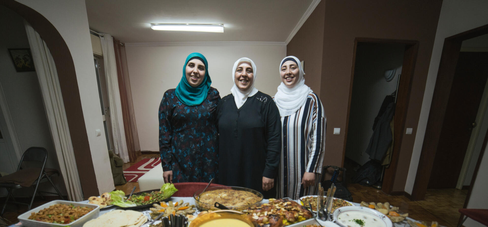 Family of chefs. Syrian refugees Fatima and her daughters Rana and Reem in front of their home cooked dishes.