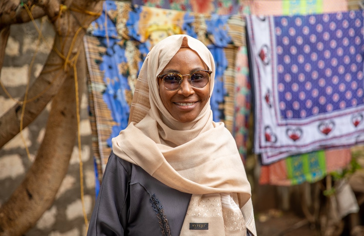 Portrait of a woman wearing glasses and a headscarf.