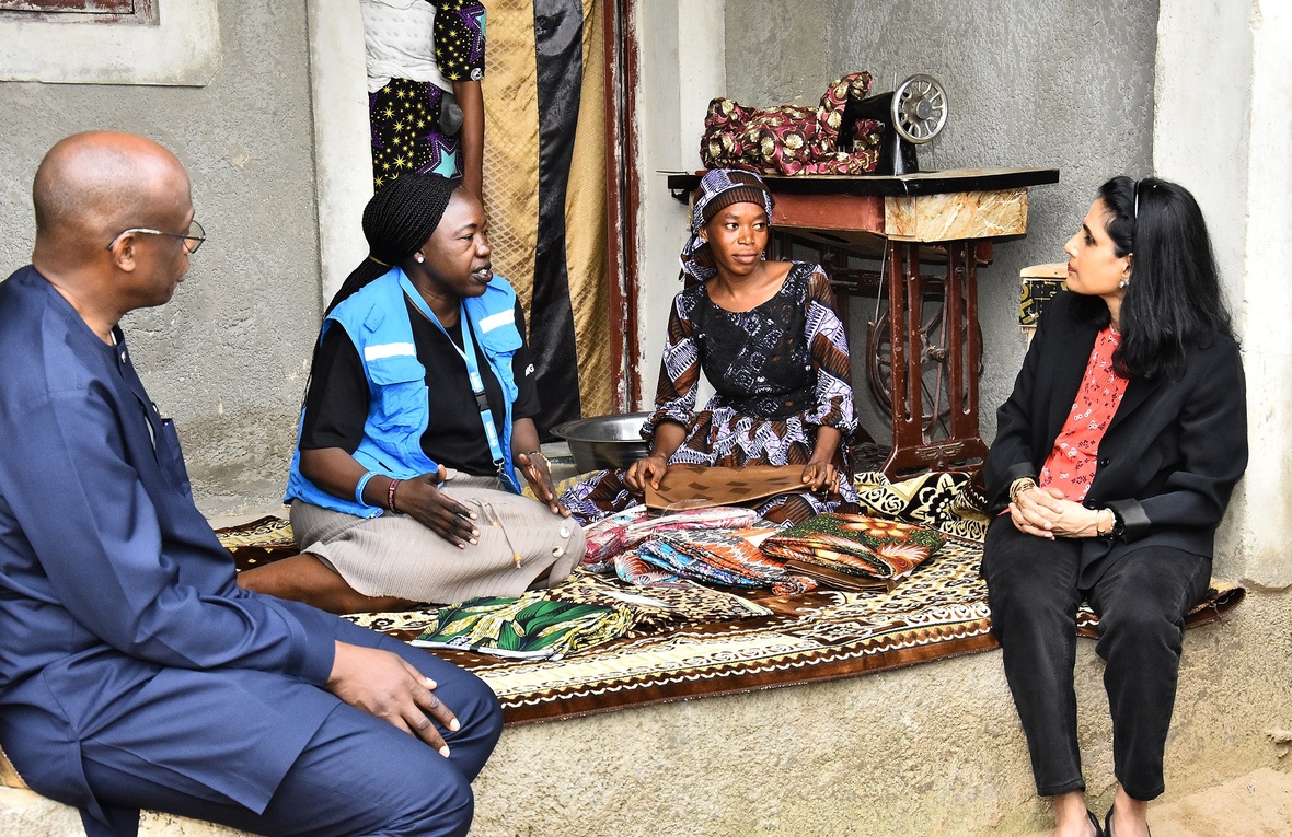 Four people sit together talking on a colourful rug