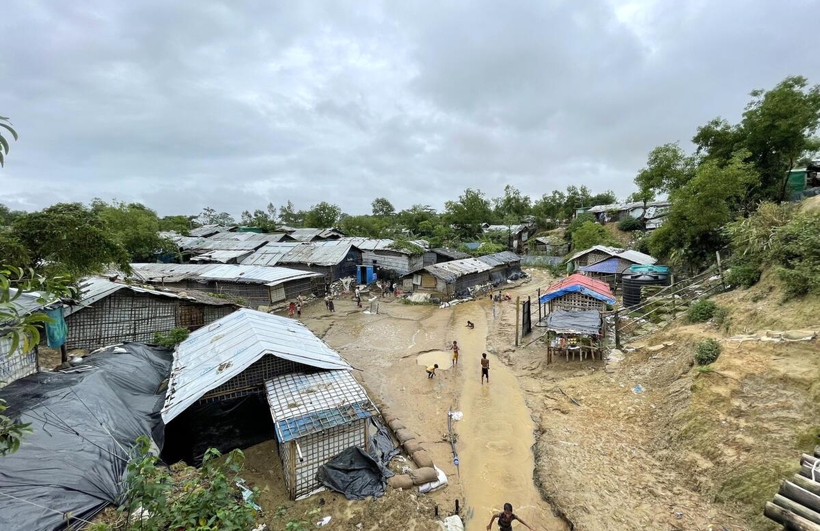 Children play in water following monsoon rains at a refugee camp.