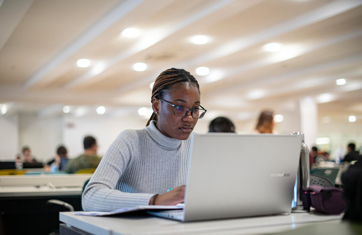 A student studies on her laptop in a university library