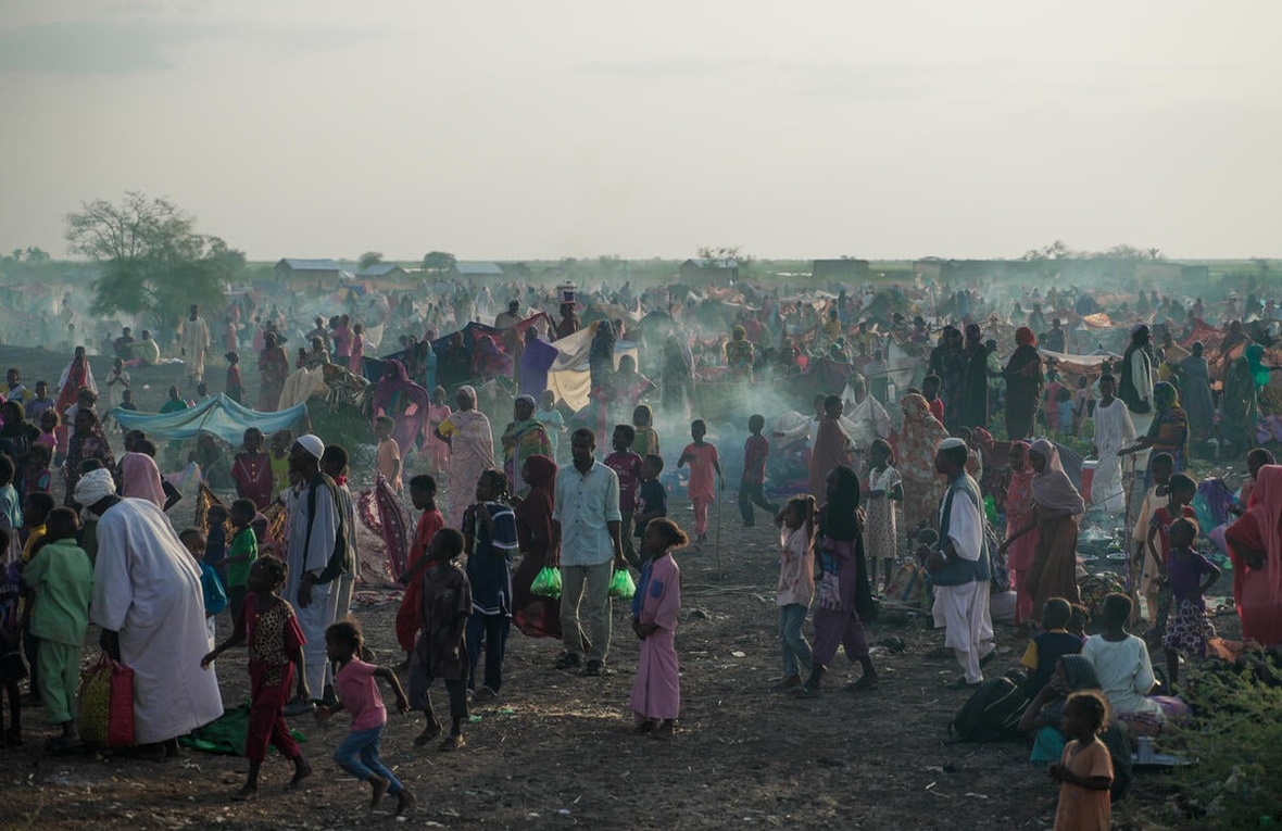 A large number of new arrivals from Sudan wait in a field in South Sudan