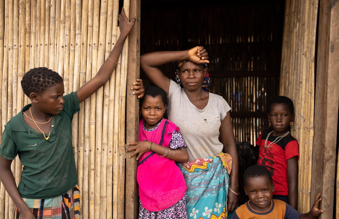 A woman and four children stand outside at a bamboo shelter