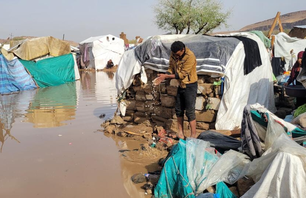 Flooding surrounds shelters and people's belongings at an IDP site.