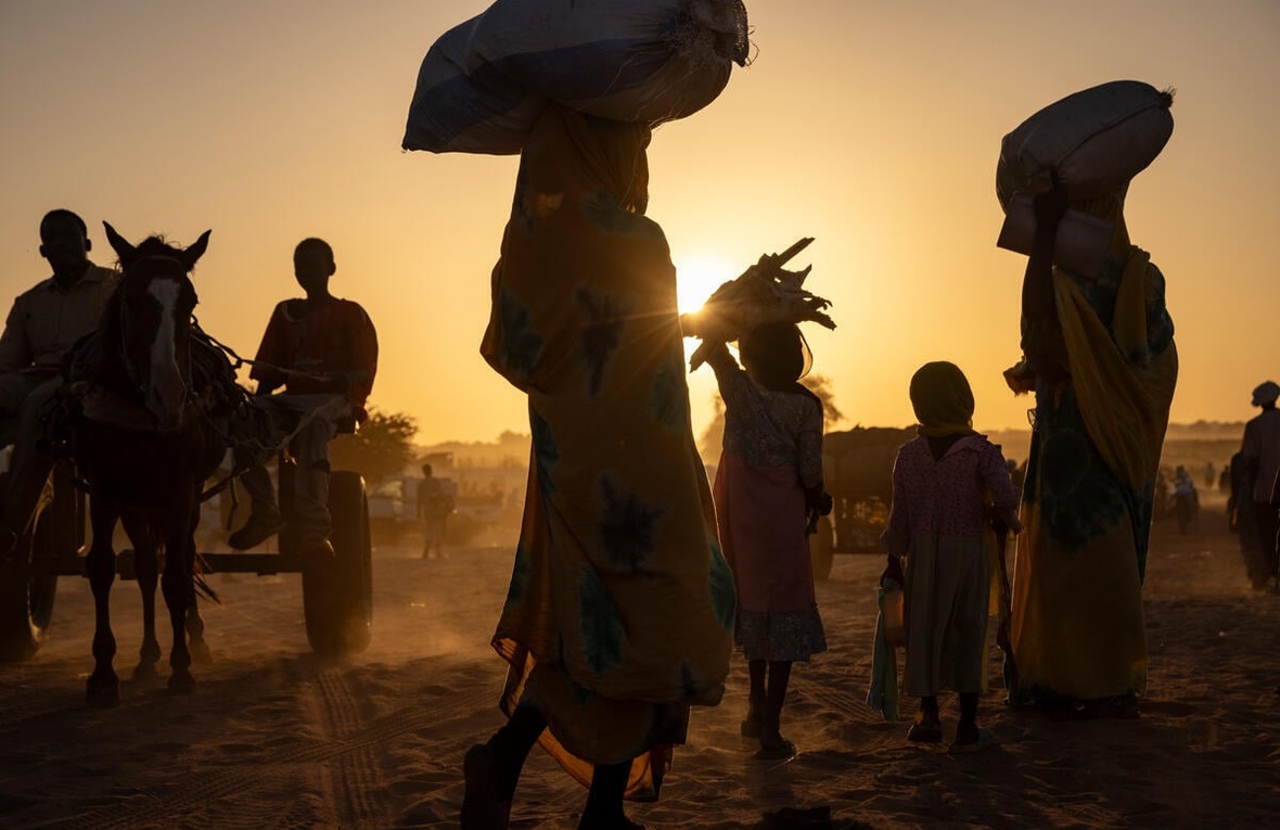 Silhouettes of a group of refugees and a horse against the sun