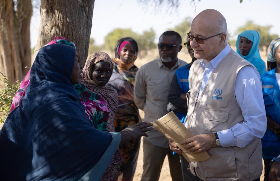 Barham Salih speaks to refugees and community members outside beside a large tree