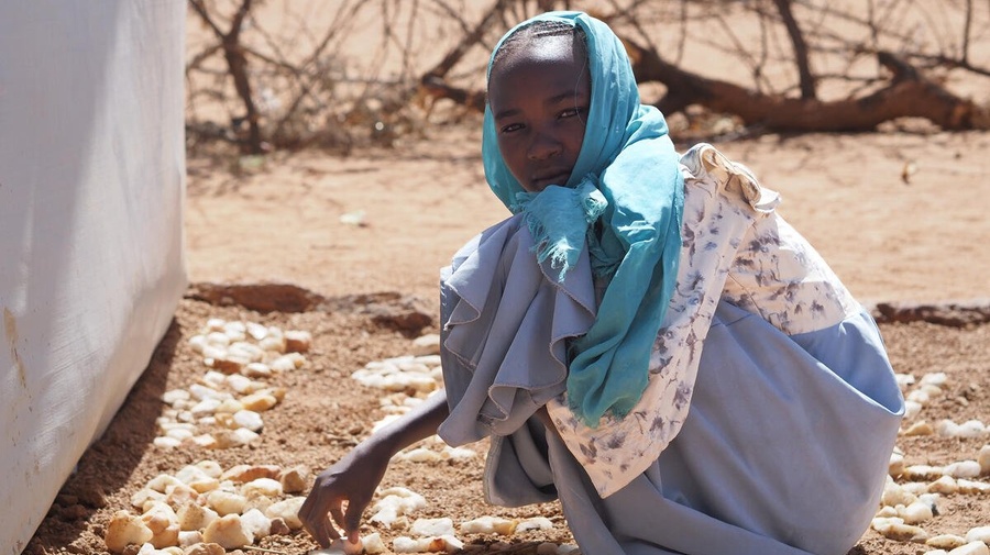 Sudanese refugee girl enjoys creating art with stones next to her new shelter in Farchana refugee settlement, eastern Chad.