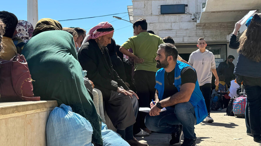 A UNHCR staff member talks to families in a crowded area