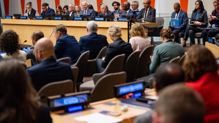 Delegates and officials attend a meeting at UN Headquarters, with speakers seated on a panel before an audience.