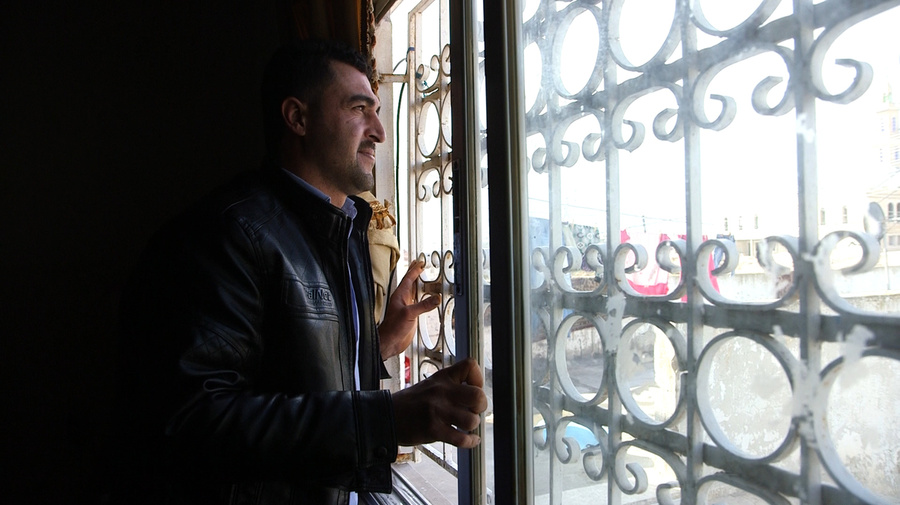 Syrian refugee Firas al Ahmad, 30, looks out of the window at his father's house in Irbid, Jordan.
