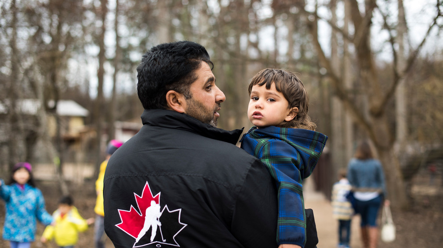 Canada. Mohammad, a Syrian refugee man carrying his youngest son at a petting zoo