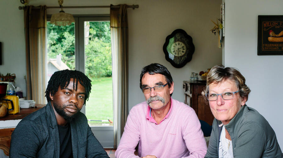 France. Catherine and Jean-Pierre host Assadik, a refugee from Sudan, in Saint-Josse. This portrait is part of the No Stranger Place series, which portrays locals and refugees living together