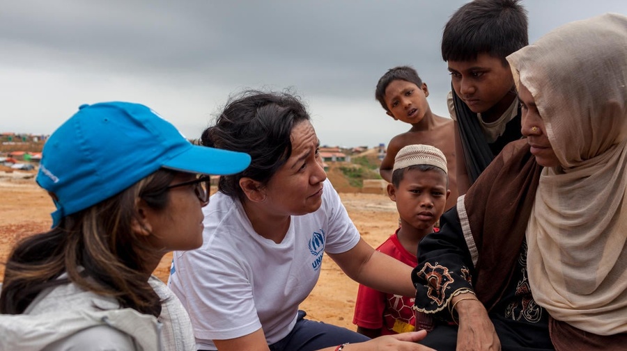 Outside. A women and three children talk with two UNHCR staff.