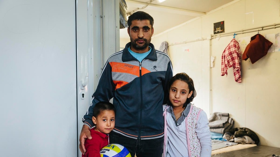 An Afghan asylum-seeker stands with two of his children at a reception centre in Fylakio, Greece, in February 2020.