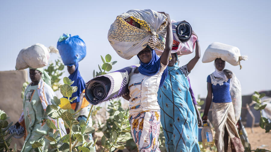 Malian refugee women carrying their belongings through Mbera refugee camp in Mali. UNHCR, UN Refugee Agency, Sexual and Gender-based Violence SGBV GBV